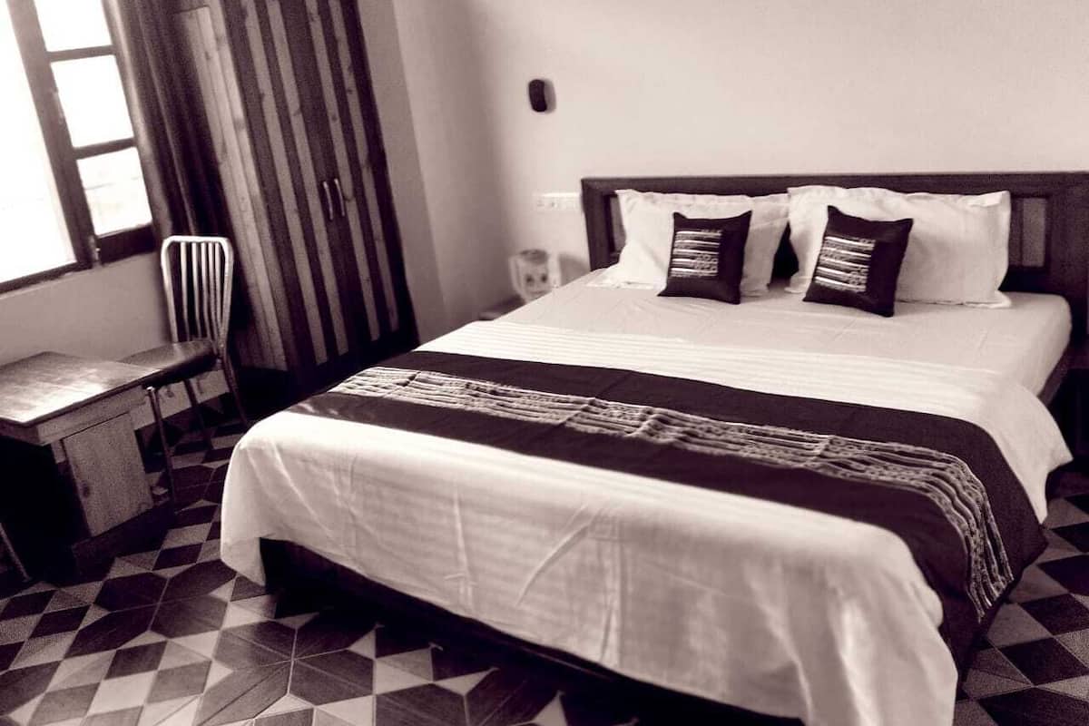A bedroom with a bed, a chair, a desk, and a wardrobe.