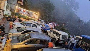 A crowded parking area with various vehicles, including cars and a bus, and a building with a signboard in the background. - Heavens Mahasu Villa By GRB (Shimla)