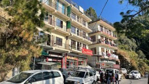 A multi-story building with balconies, a bank, and parked cars. - Heavens Mahasu Villa By GRB (Shimla)