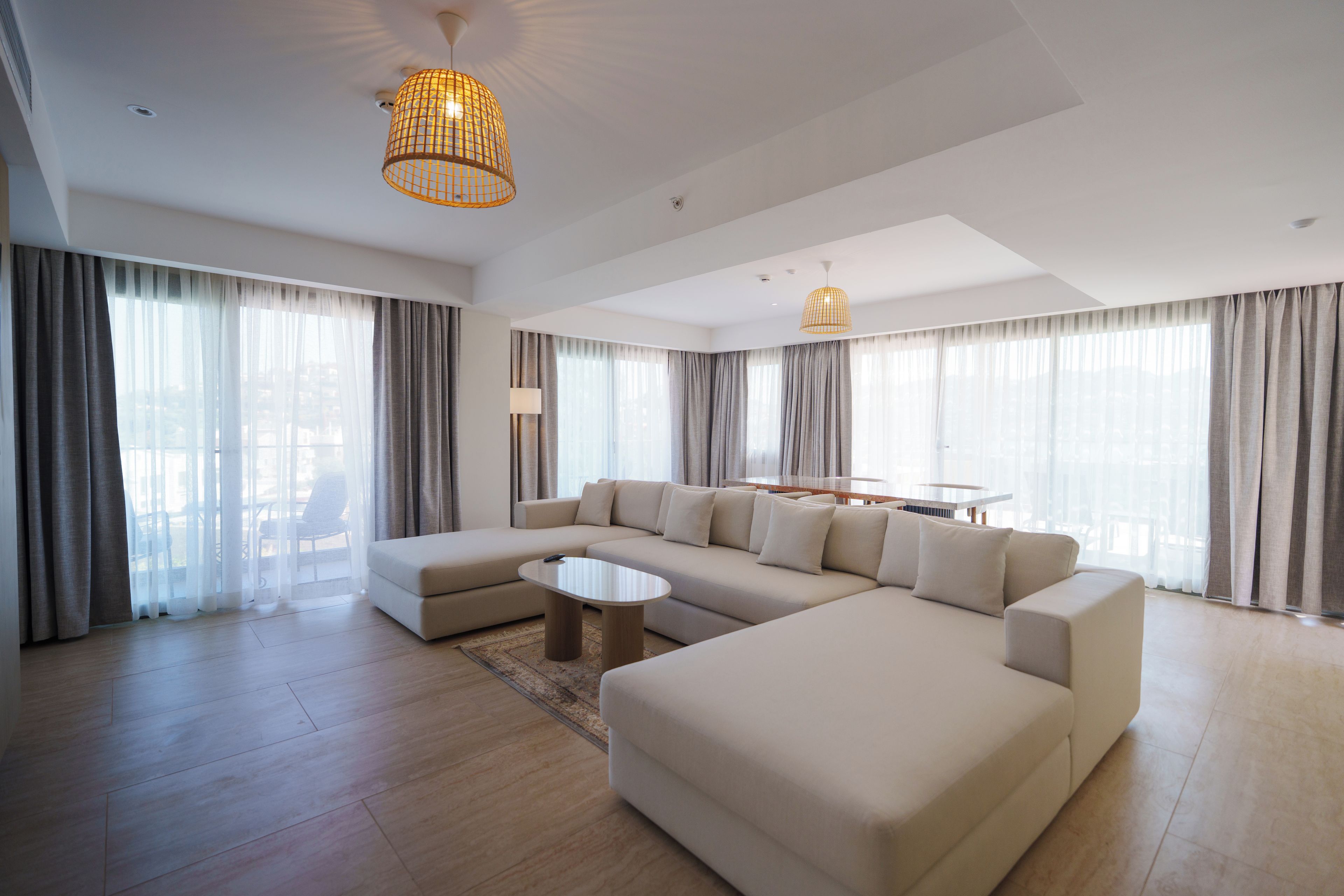 A modern living room with a sectional sofa, a coffee table, and a dining area with a table and chairs.