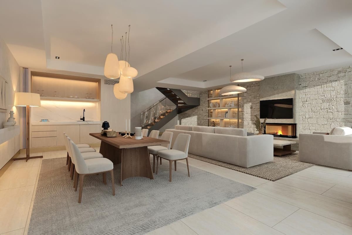 A modern living room with a fireplace, a dining area with a wooden table and chairs, and a staircase leading to an upper level.