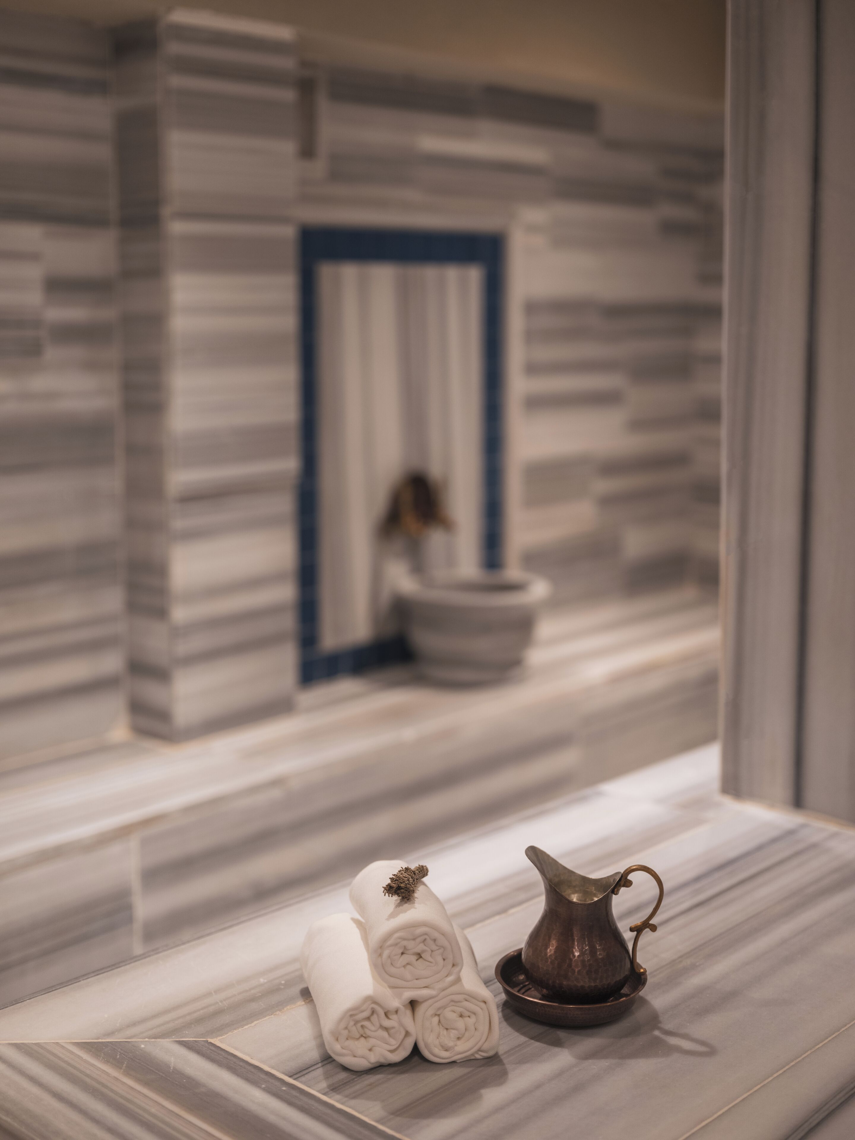 Une salle de bain carrelée de marbre, avec un porte-serviettes et un pichet décoratif.
