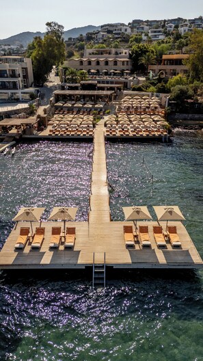 A wooden pier with sun loungers and umbrellas extending into a body of water.