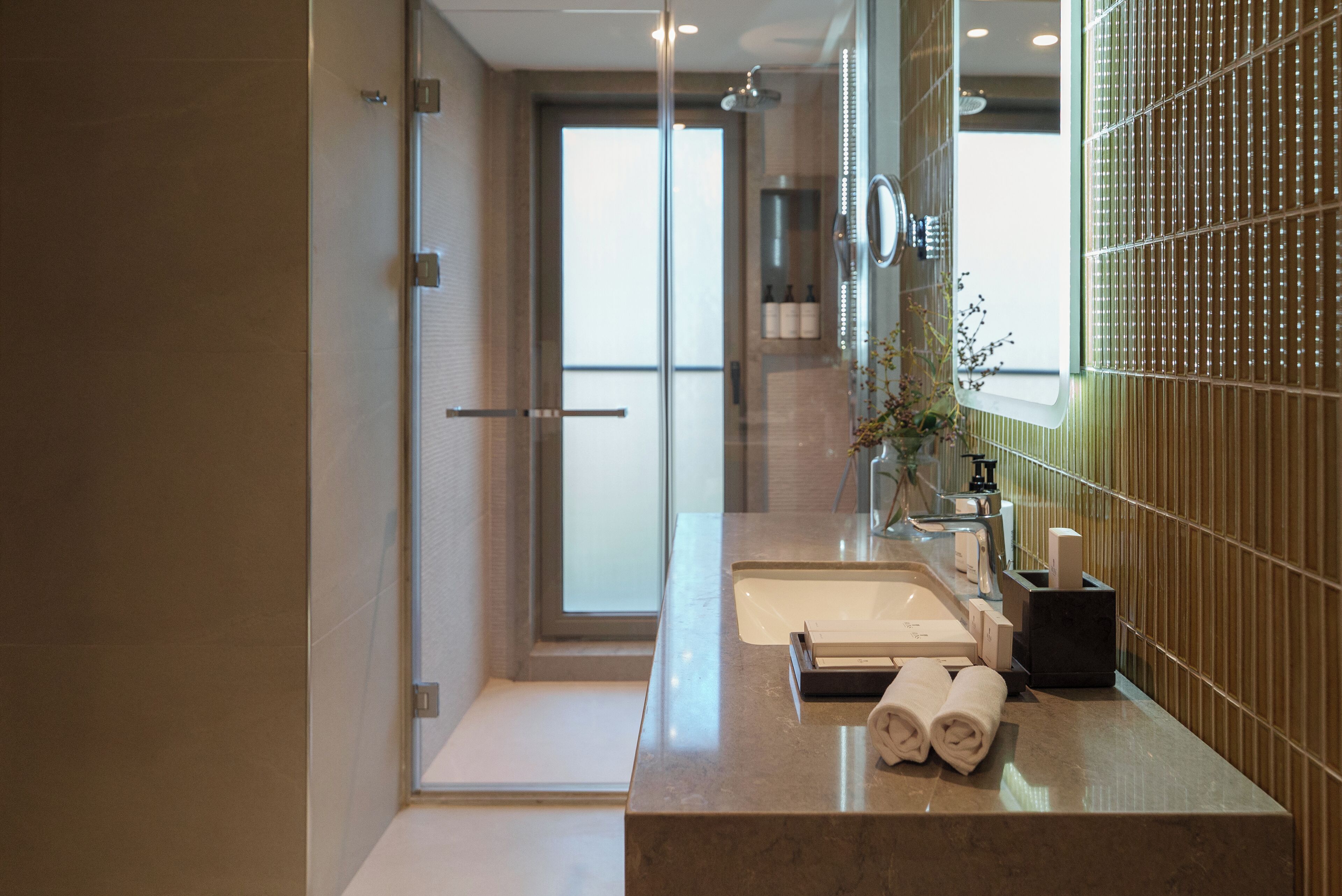 Un baño moderno con cabina de ducha de vidrio, un espejo grande y encimera de mármol.
