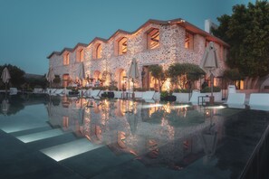 A stone building with a pool, outdoor seating, and umbrellas. - Ruins Luxury Resort (Bodrum)