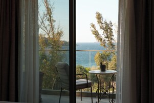 Un balcón con vista al mar, una silla y una mesa con una planta en maceta.