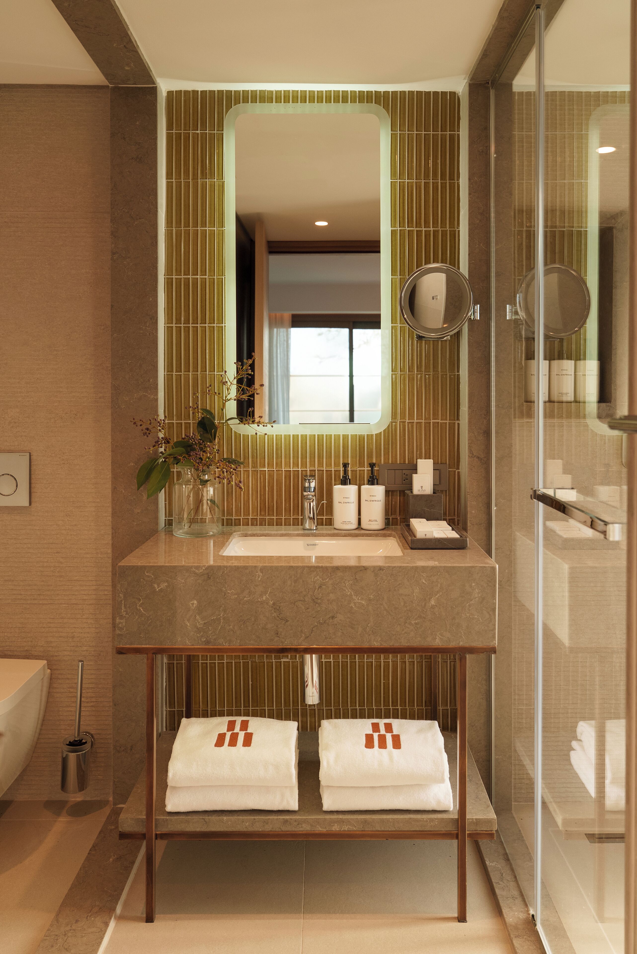 A modern bathroom with a large mirror, two sinks, and a glass-enclosed shower.