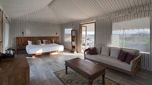 Une pièce spacieuse avec un grand lit, un canapé et une table en bois. Une fenêtre offre une vue sur le paysage.
