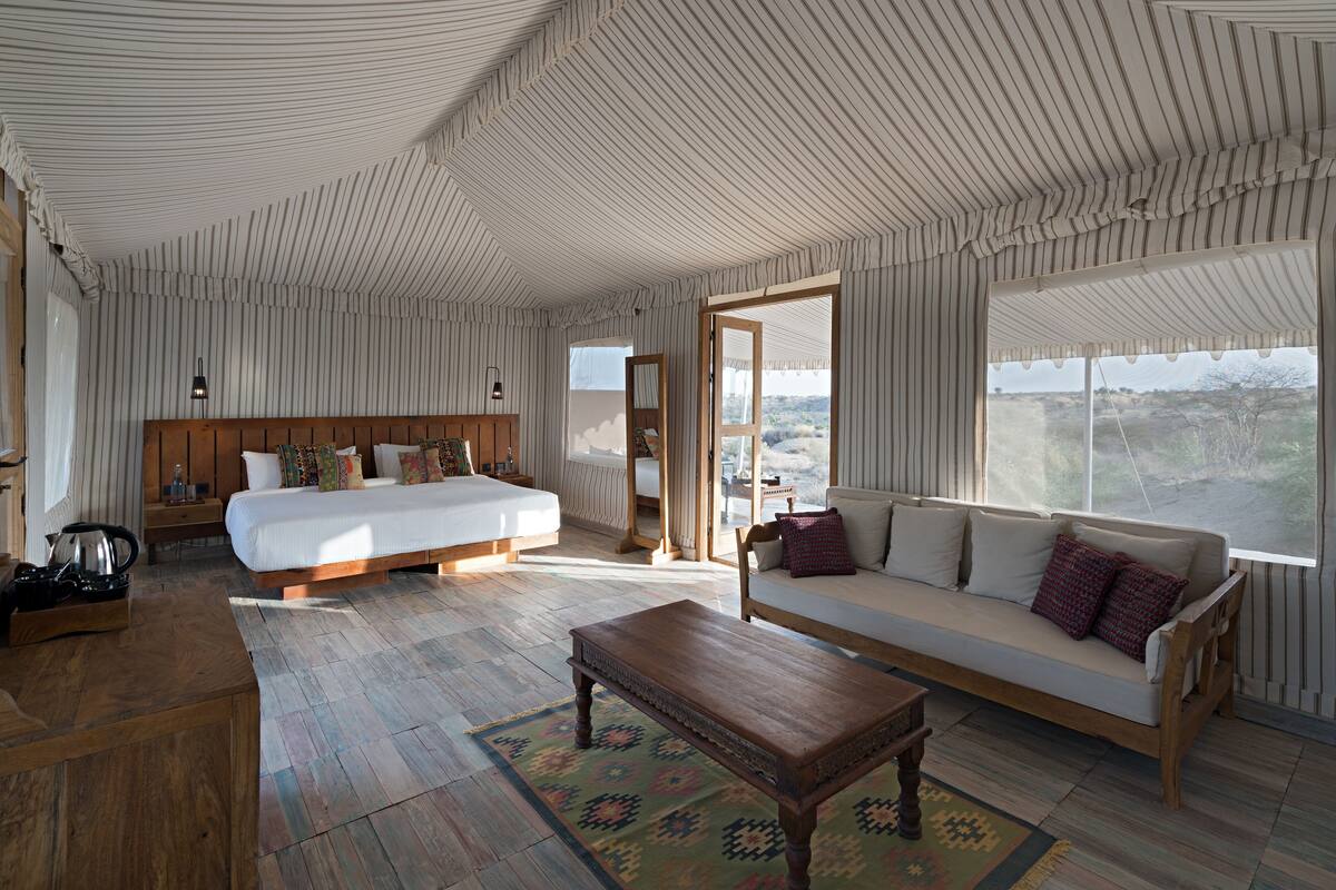 Um quarto espaçoso com uma cama grande, um sofá e uma mesa de madeira. Há uma janela com vista para a paisagem.