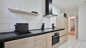 A modern kitchen with a black countertop, wooden cabinets, a built-in oven, and a black range hood. - Goodliving Apartments | Netflix*Office*Parking (Essen)