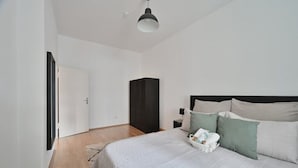 A bedroom with a bed, bedside table, and a wardrobe. - Goodliving Apartments | Netflix*Office*Parking (Essen)