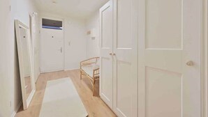 A hallway with white doors, a bed, and a small window. - Goodliving Apartments Studio Balcony Netflix (Essen)