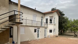A two-story building with a staircase, multiple windows, and a dirt ground area.