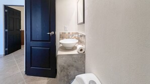 A bathroom with a dark door, a white sink, a towel, and a toilet paper holder. - Best Location + Clean, Safe, Just Built (Sayulita)