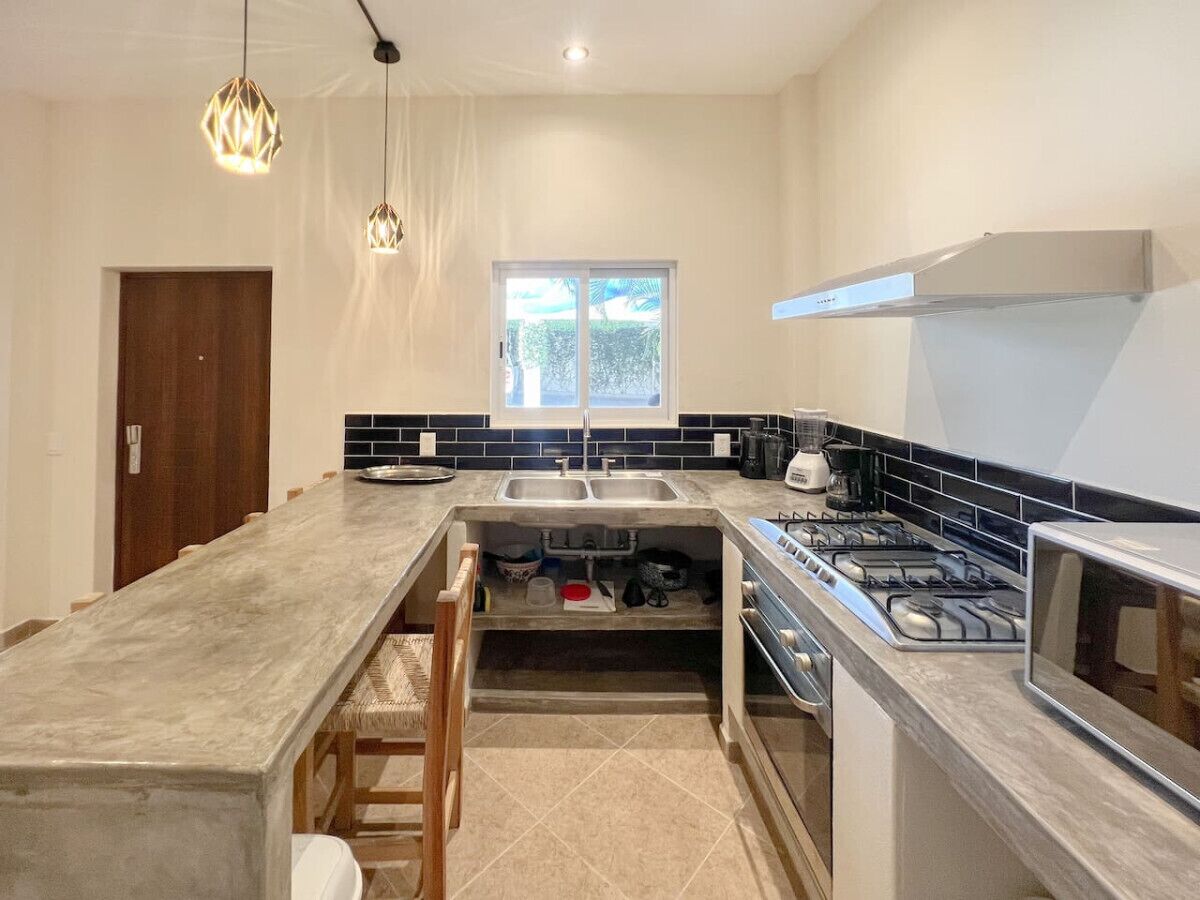 A modern kitchen with a long island, double sink, and gas stove.