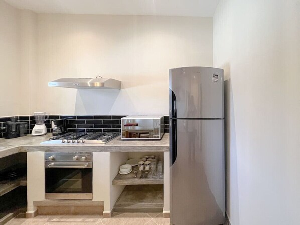 A modern kitchen with a built-in oven, a gas stove, a stainless steel refrigerator, and a microwave.