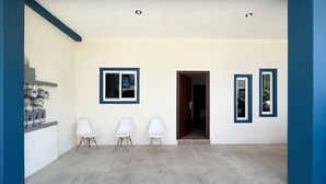 A spacious entryway with a concrete floor, three white chairs, and a wooden door. - Best Location + Clean, Safe, Just Built (Sayulita)