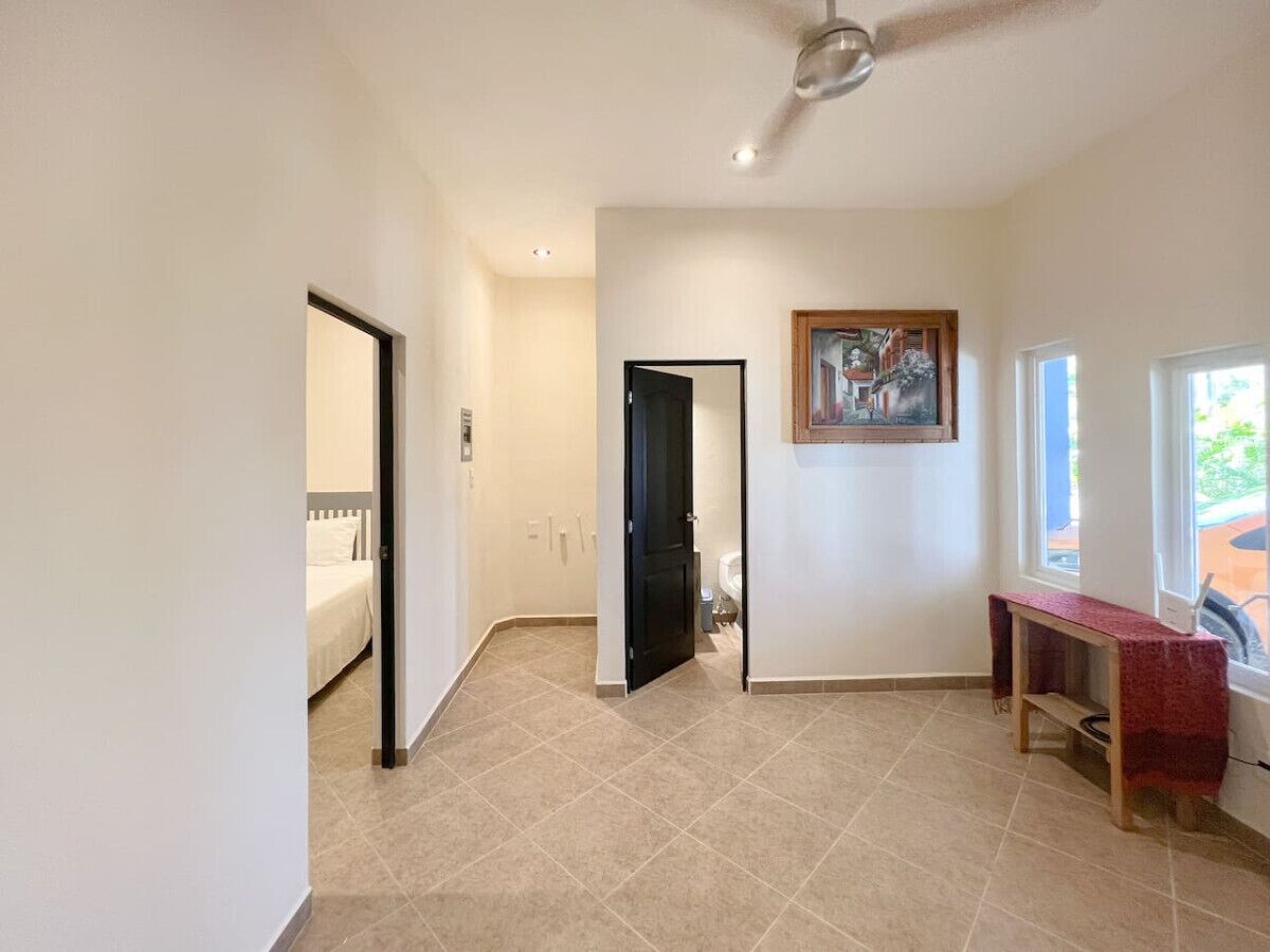 Un hall d’entrée spacieux, doté d’un ventilateur de plafond, d’une porte donnant sur une chambre et d’une petite table près d’une fenêtre.