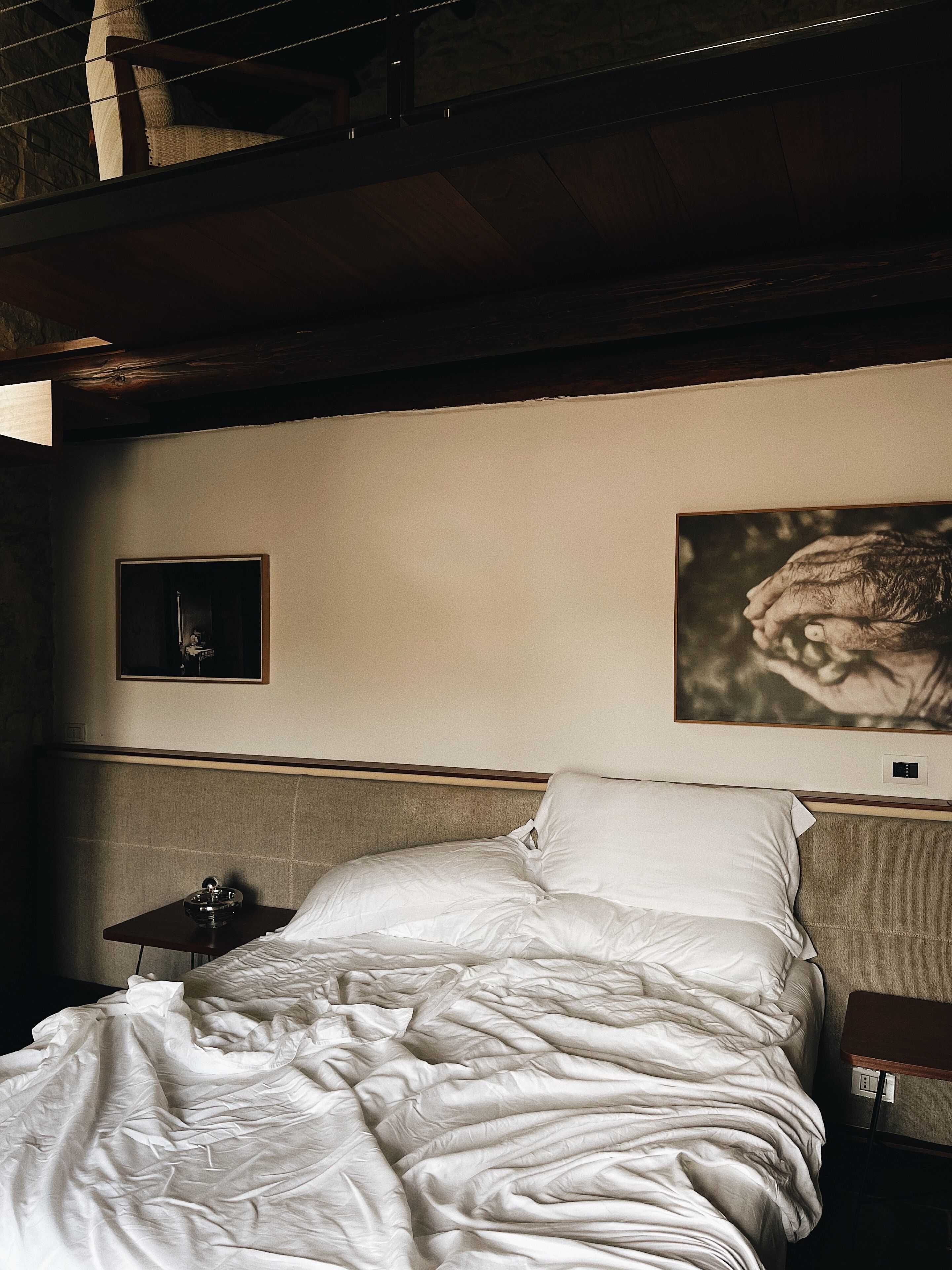 Een hotelkamer met een bed, een nachtkastje en twee ingelijste foto's aan de muur.