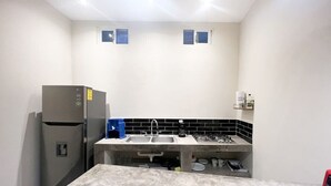 Une cuisine de taille réduite, équipée d’un réfrigérateur, d’un évier à deux bacs et d’un petit plan de travail.