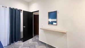 Un couloir avec une porte, un miroir et une étagère.