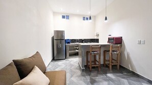 Un espace de vie compact comprenant un coin cuisine, un canapé et un coin repas avec deux chaises.