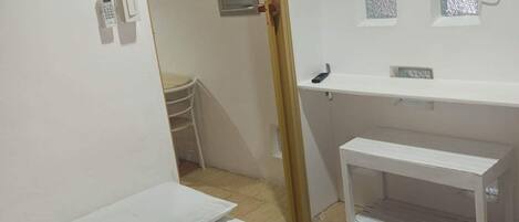Habitación de hotel con cama, televisión montada en la pared, mesita de noche y una pequeña estantería.