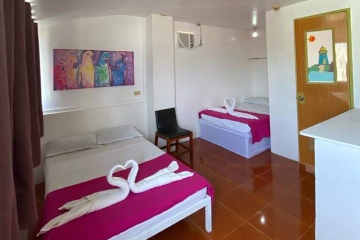 A hotel room with two beds, a chair, a painting on the wall, and a door with a picture.