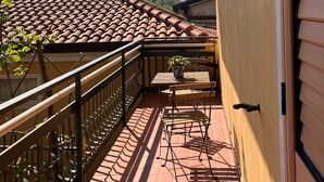 Un balcon doté d’un toit en tuiles, d’une pancarte d’accueil et d’une plante en pot.