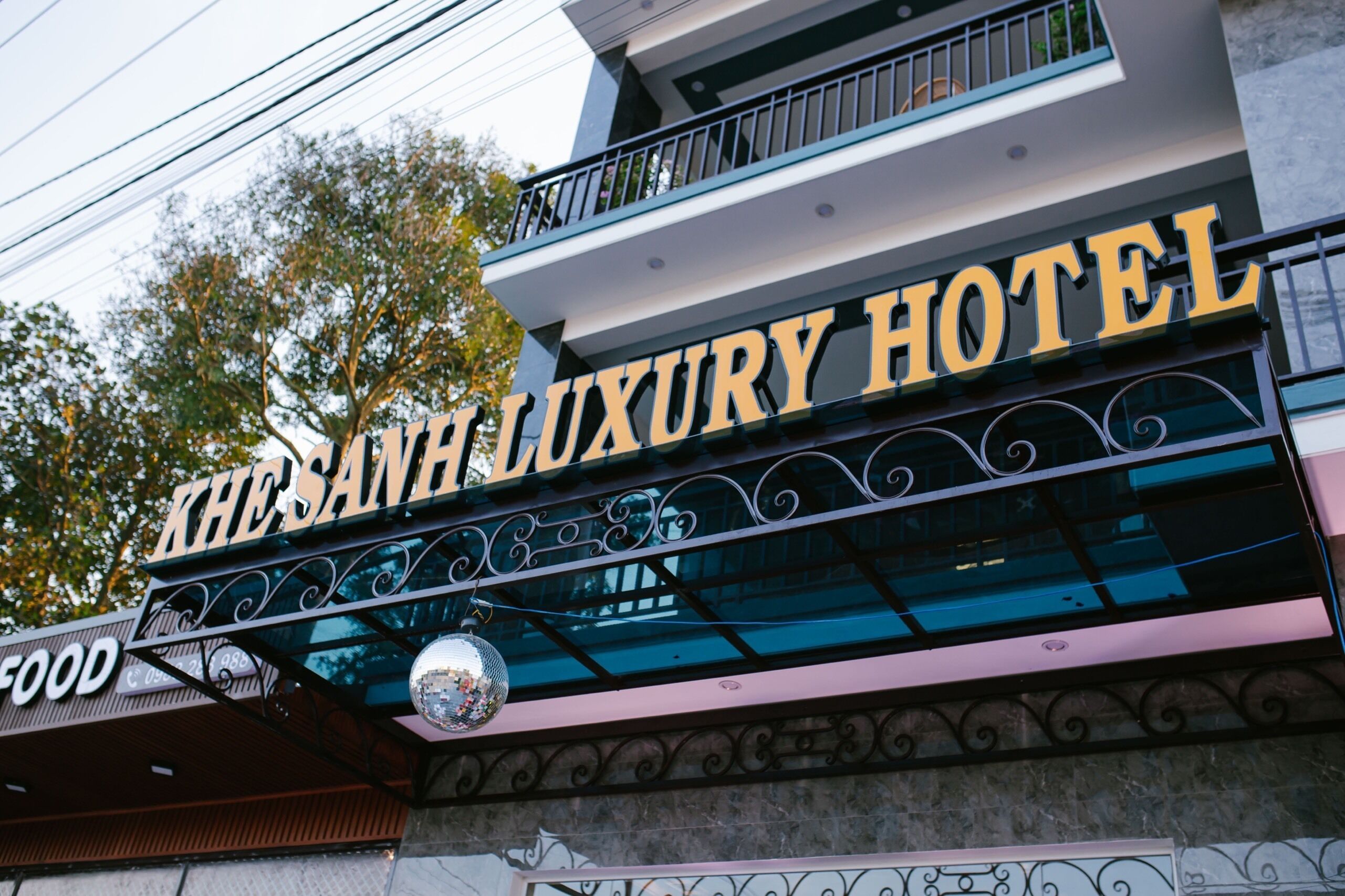 A sign for Khe San Luxury Hotel with a balcony and decorative metalwork.