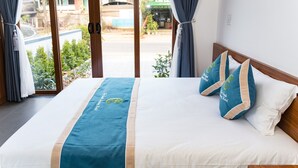 A hotel room with a bed, curtains, and a view of the street outside.