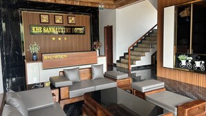 A reception area with a wooden reception desk, a wall-mounted clock, and a staircase leading to an upper level.
