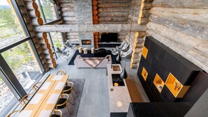 A log cabin interior with a stone fireplace, seating area, and a dining table. - Luxury Villa Utsun Otso with breathtaking landscapes.  (Sirkka)