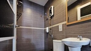 Een badkamer met donkere betegelde wanden, een wit toilet, een wastafel op voet en een douchehoek.