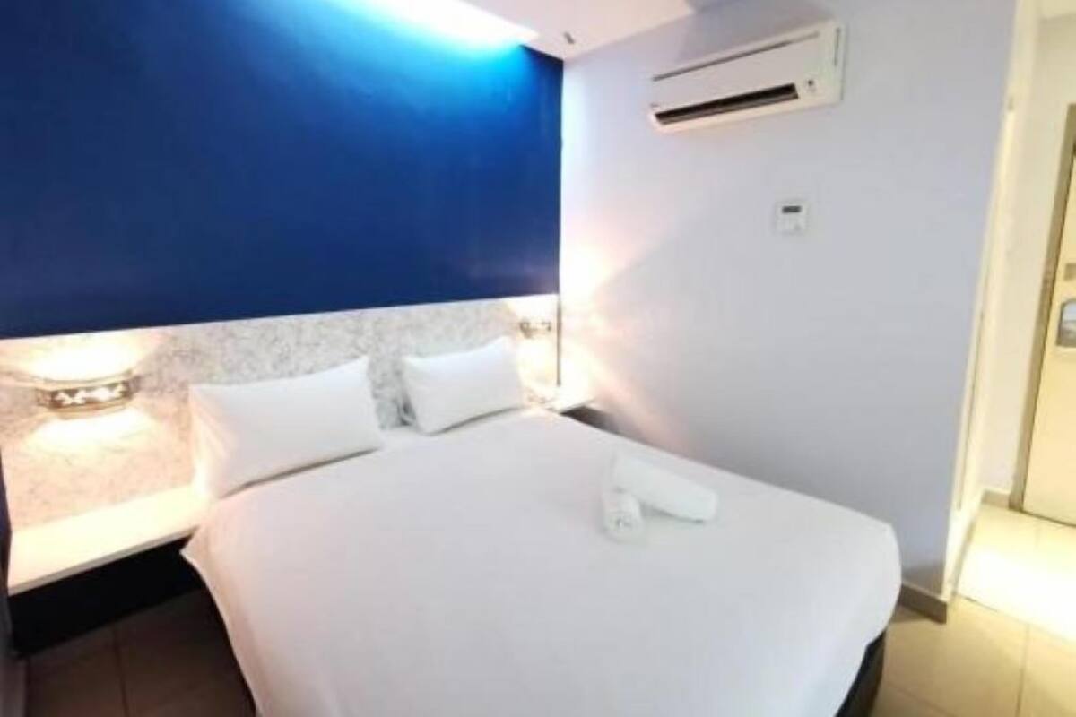 Ein Hotelzimmer mit einem großen Bett, einem Nachttisch und einer Wand-Klimaanlage.