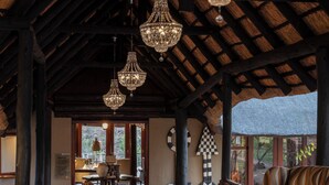 Un hall d’entrée spacieux avec un plafond haut, des lustres décoratifs, un tapis à motifs et un coin salon confortable.