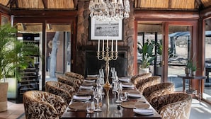 Un espace repas agrémenté d’un grand lustre, d’un plafond en bois et de chaises à motifs.