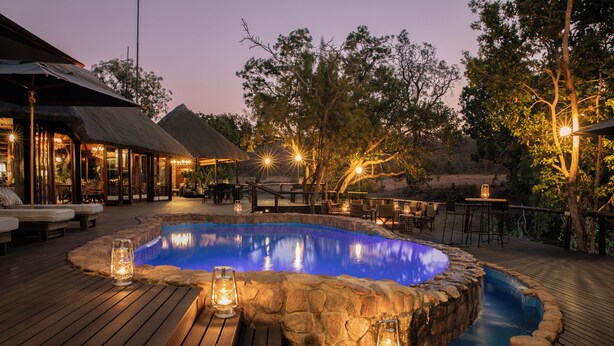 Une terrasse en bois avec un jacuzzi, des murs en pierre et des lanternes.