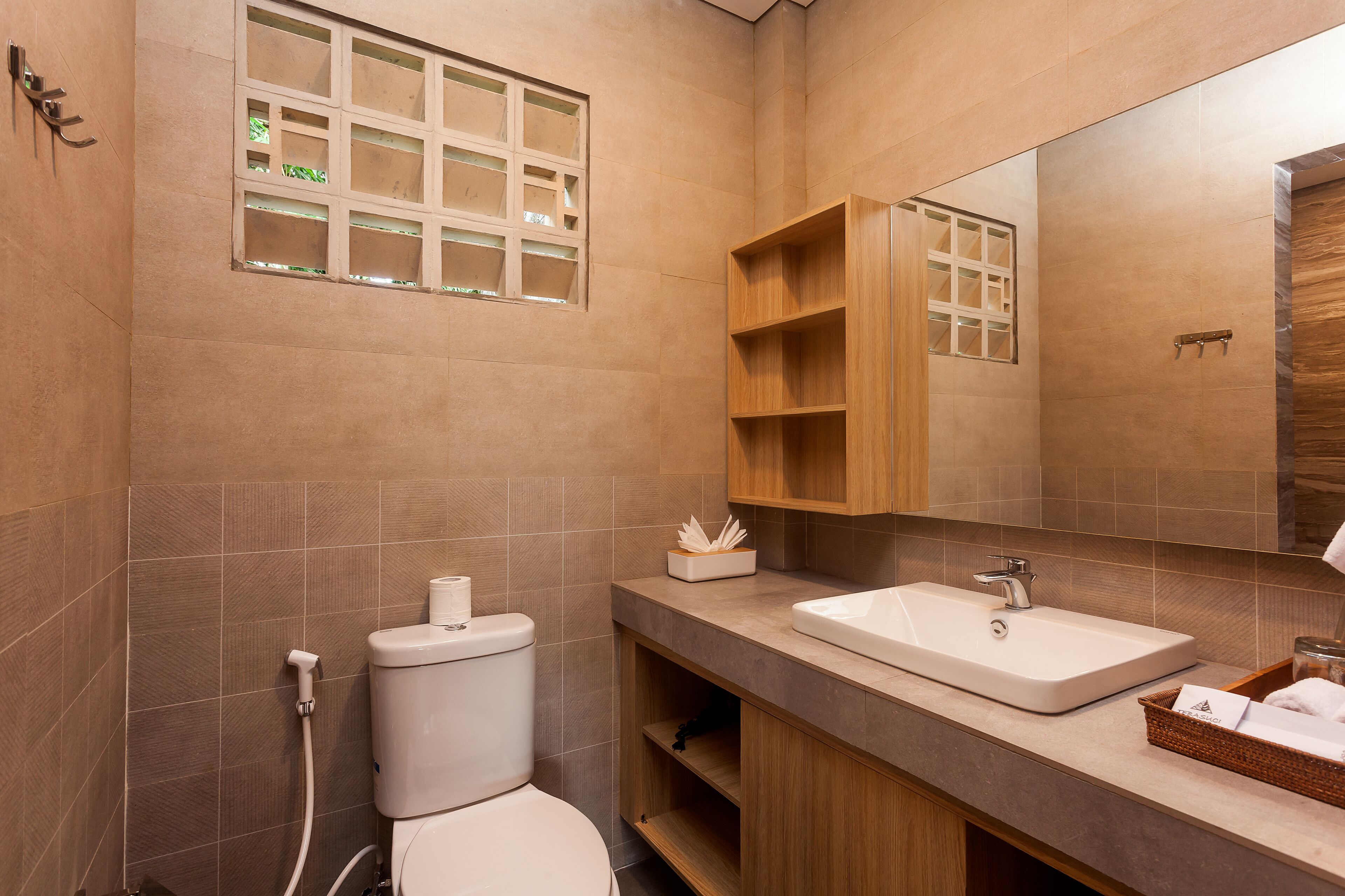 A modern bathroom with a toilet, sink, and wooden shelves.