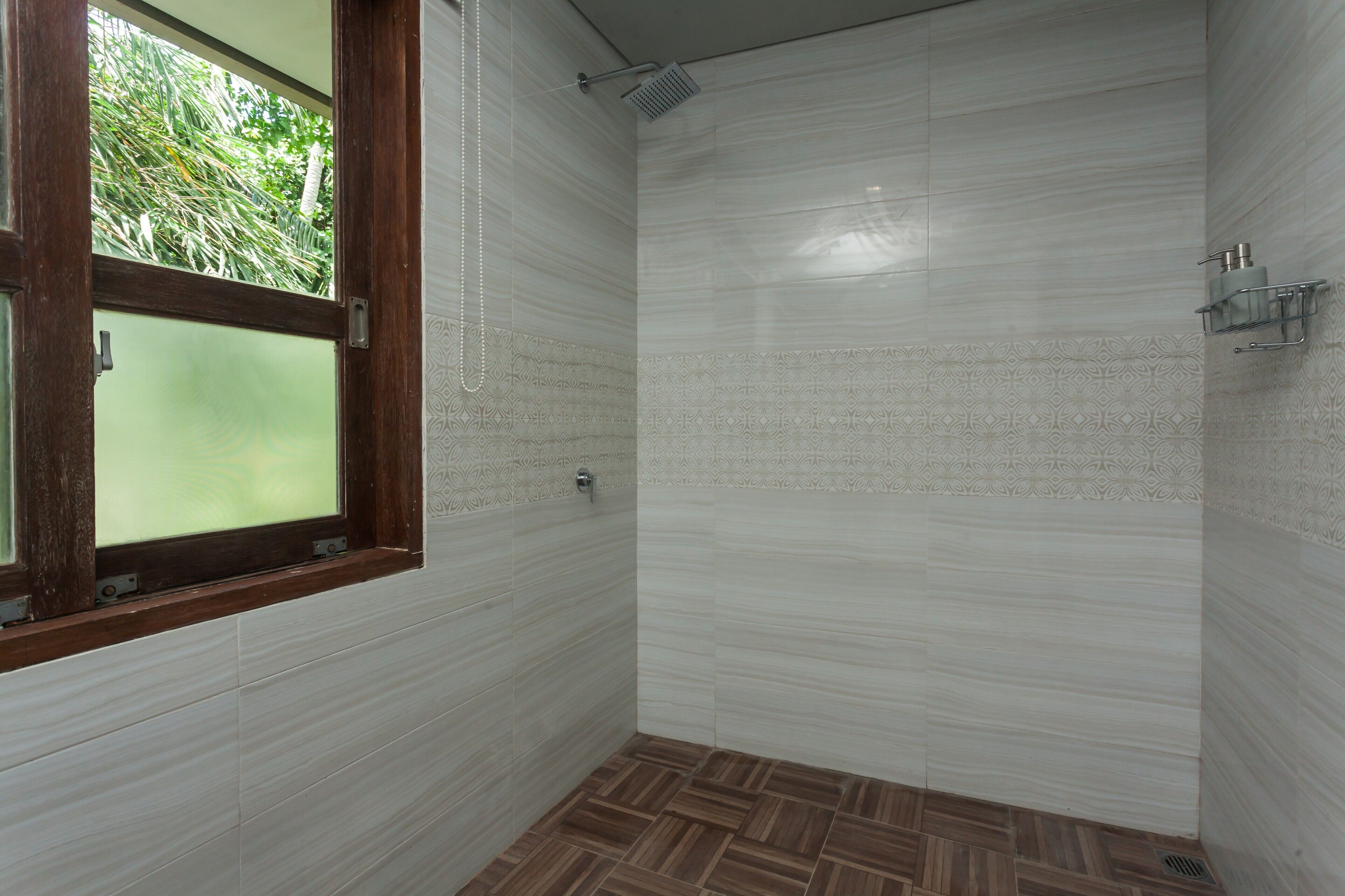A shower area with a wooden window, tiled walls, and a patterned floor.
