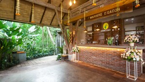 Un interior rústico con mostrador de ladrillo, luces colgantes y vegetación en el exterior.