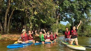 People on kayaks in a river surrounded by trees.