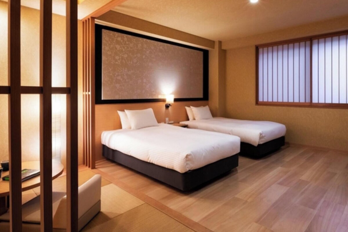 Une chambre d’hôtel avec deux lits, un bureau et une chaise.