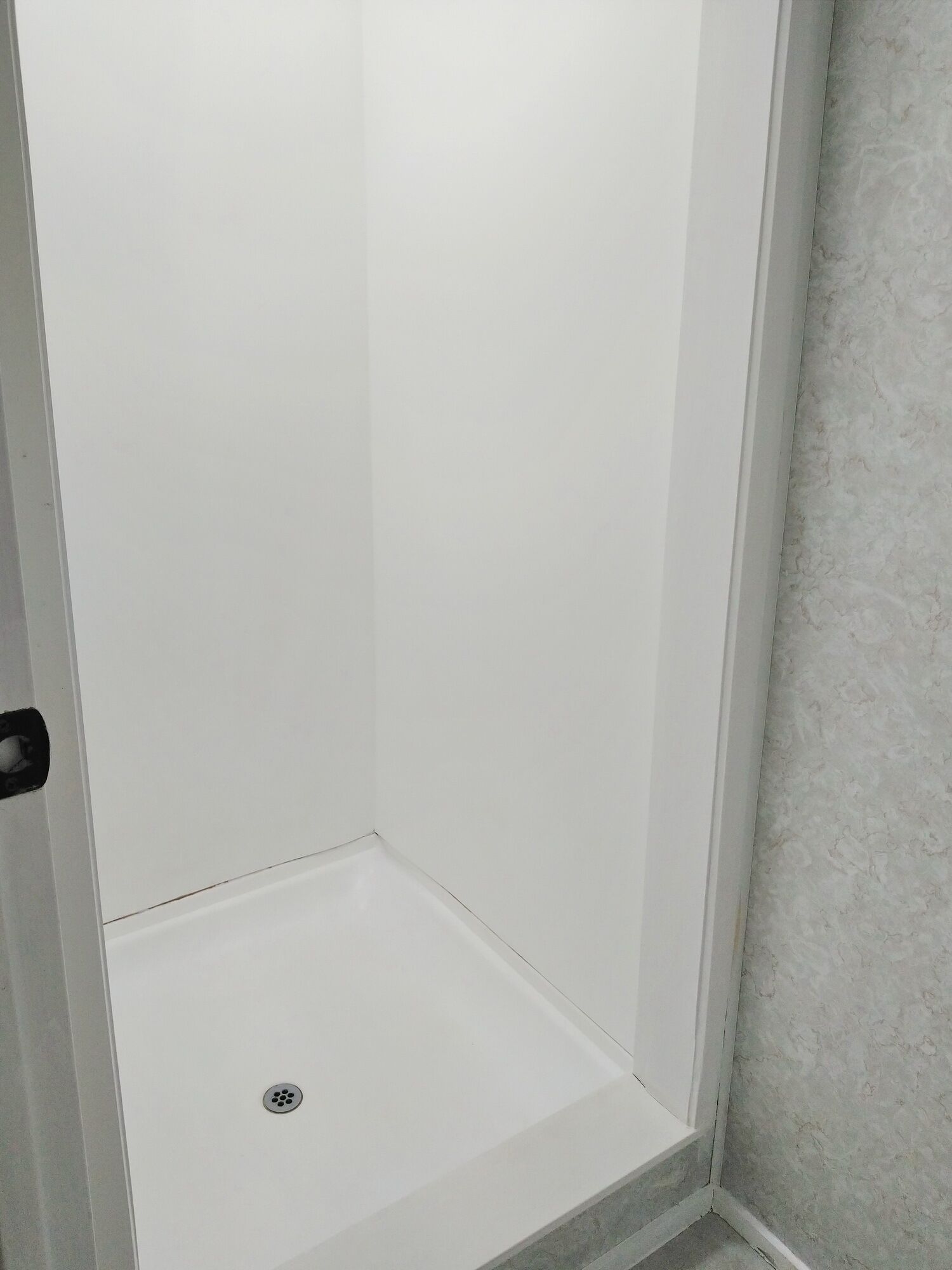 A corner of a room with a white door and a textured wall.