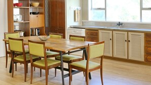 Un comedor con mesa y sillas de madera, una cocina con armarios de madera, y un ventanal con vistas.