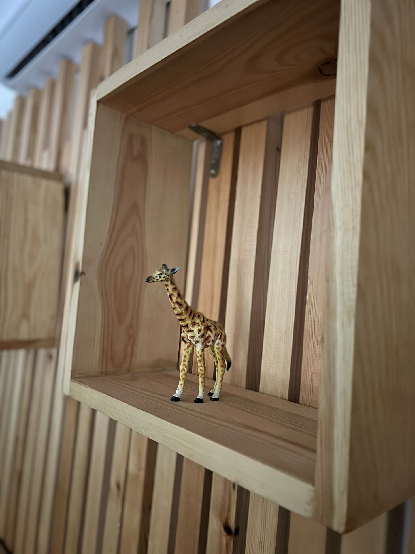 Une étagère en bois sur laquelle est posée une figurine de girafe.