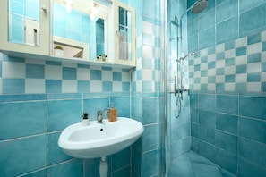 Bathroom features a checkered tile pattern, a sink with a soap holder, and a shower area with glass doors.