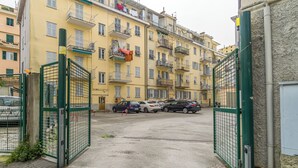 Un estacionamiento con varios autos estacionados frente a un edificio amarillo con balcones.