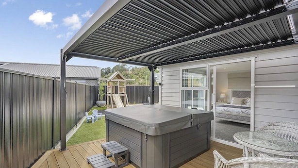 A covered outdoor area with a hot tub, wicker chairs, and a wooden deck. - Private Ensuite with Hot Spa at Upper Hutt, Wellington (Upper Hutt)