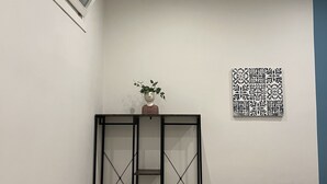 A corner room with a black metal cabinet, a chair, a small table, a wall-mounted picture, and a ceiling light. - B&b Margherita Torremaggiore (Torremaggiore)